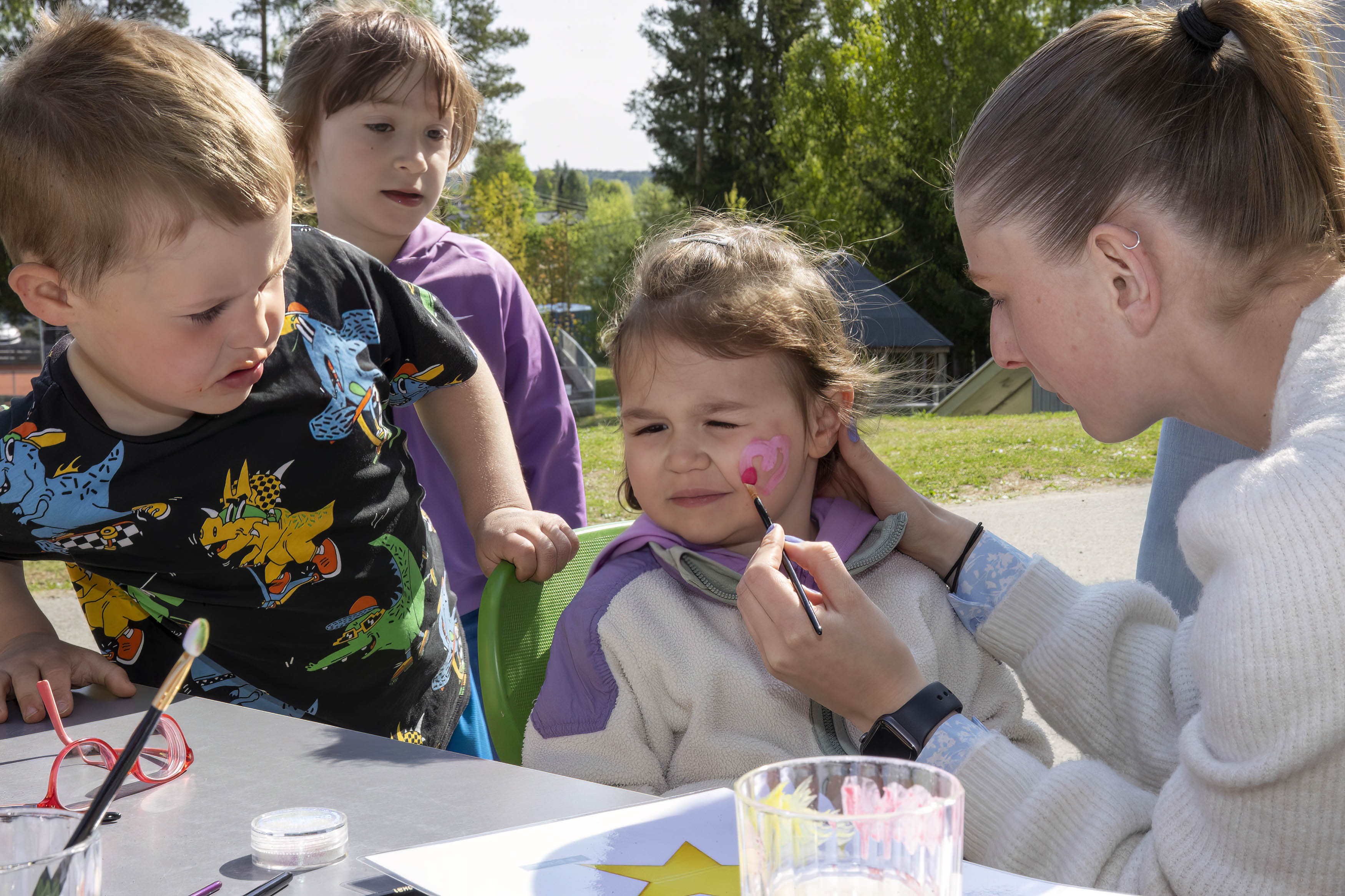 Her får 3 år gamle Tia Paola Kolovrat malt et hjerte på kinnet. Dennis Larsen Kolderup og Danijela Ahmetovic følger godt med